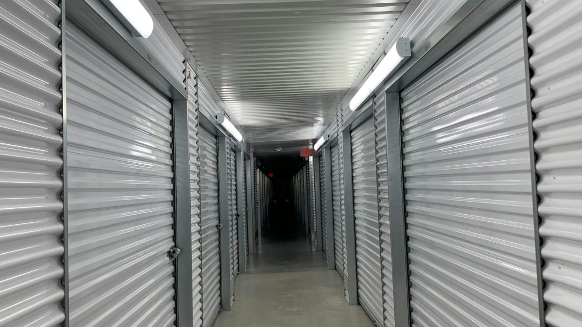 Long indoor hallway of climate-controlled self storage units with metal roll-up doors